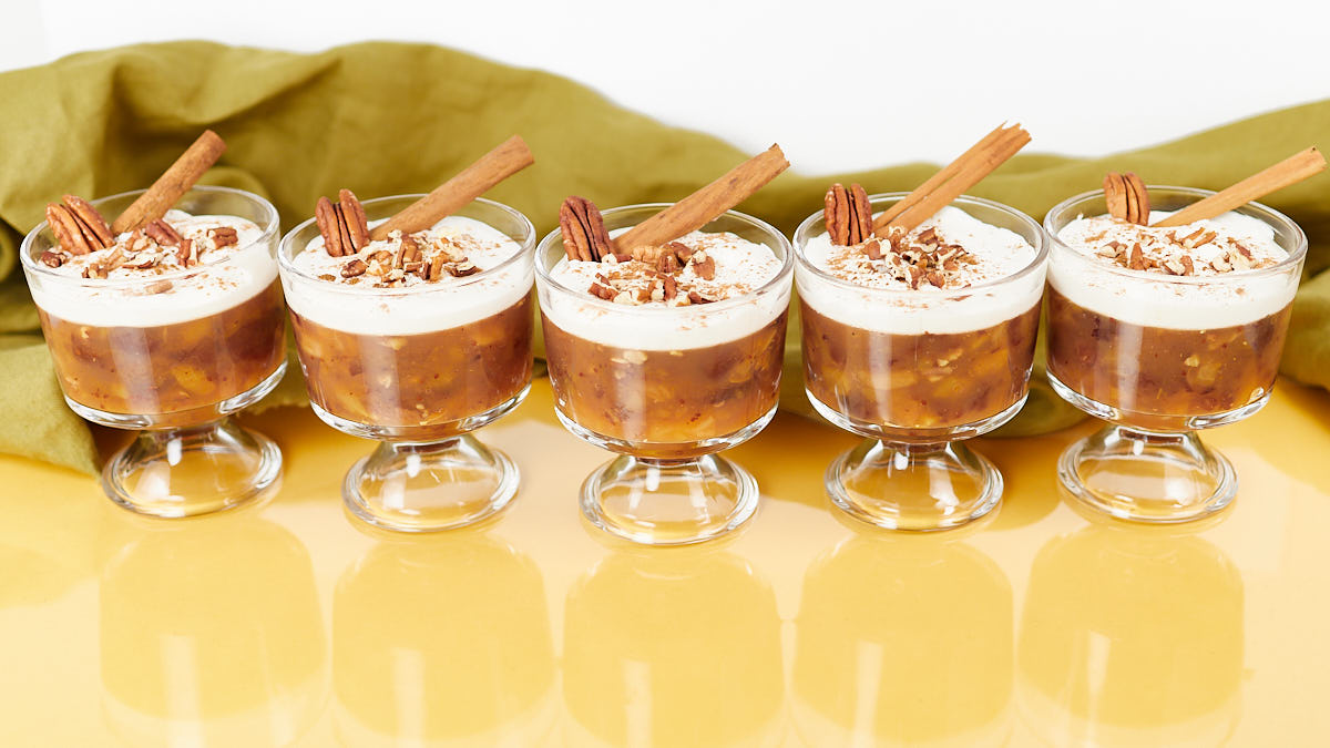 Five apple cider and cranberry jello salads in footed glasses lined up.