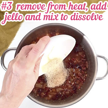 Adding orange jello powder to mix in saucepan.