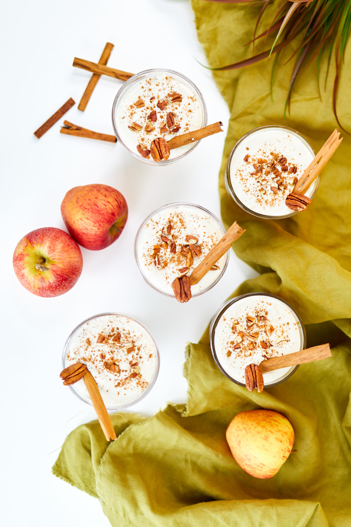 Apple cider desserts on a table with apples and cinnamon sticks.