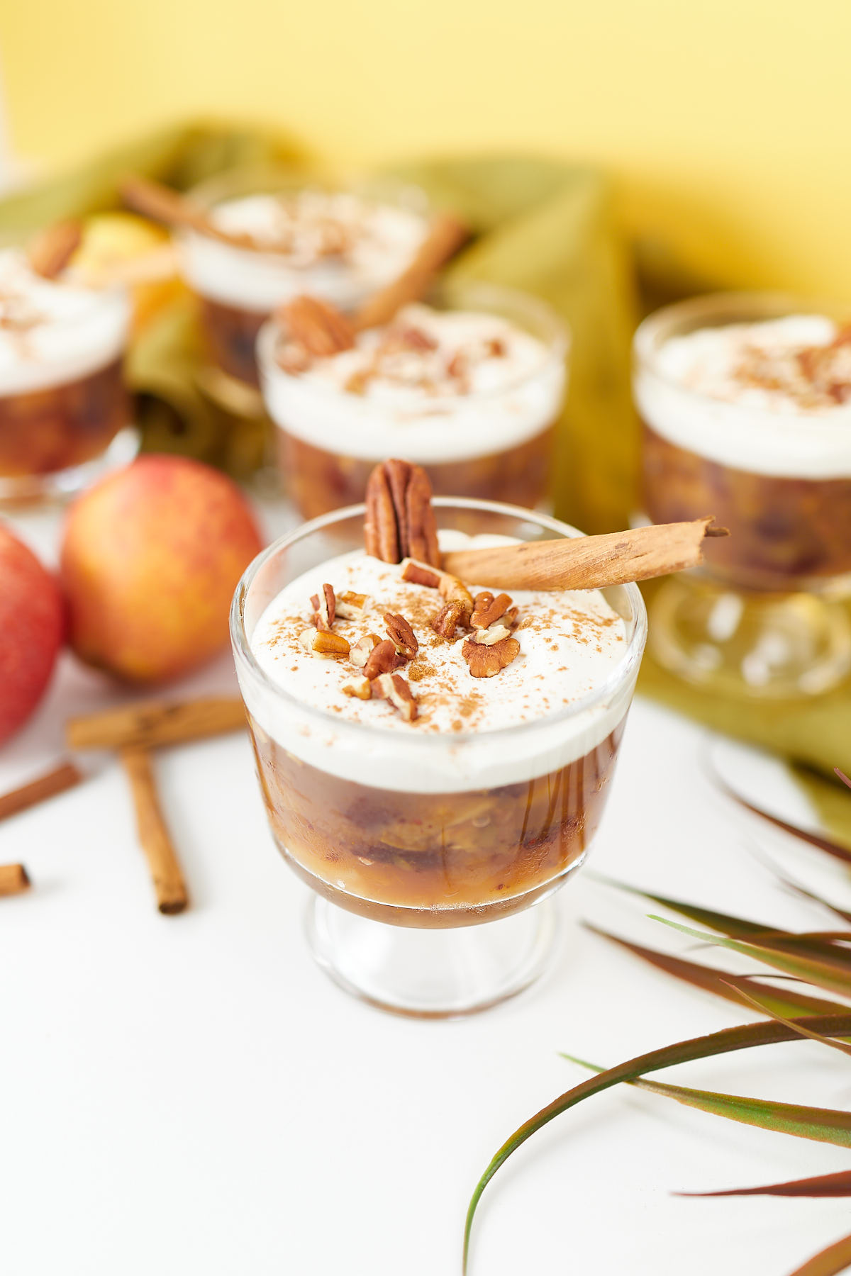 Apple and cranberry jello salad served in an elegant glass with creamy topping and crushed pecans.