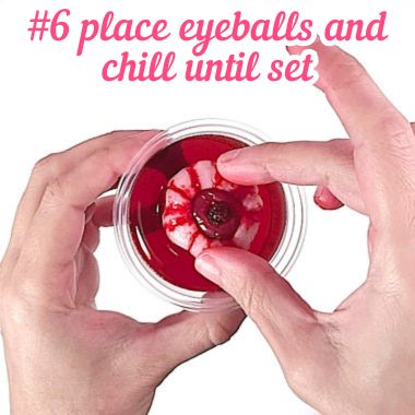 Placing lychee eyeballs on center of cups with partially set jello.
