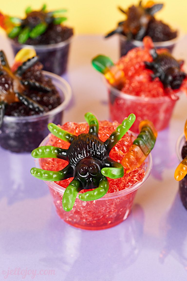 Gummy spider on a jello shot cup filled with red crushed jello.