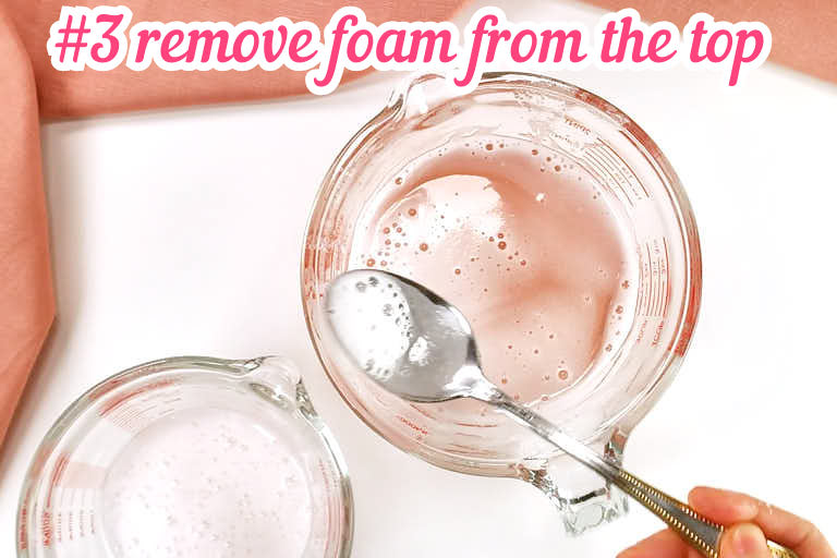 Removing excess foam from top of liquid gelatin with a spoon.